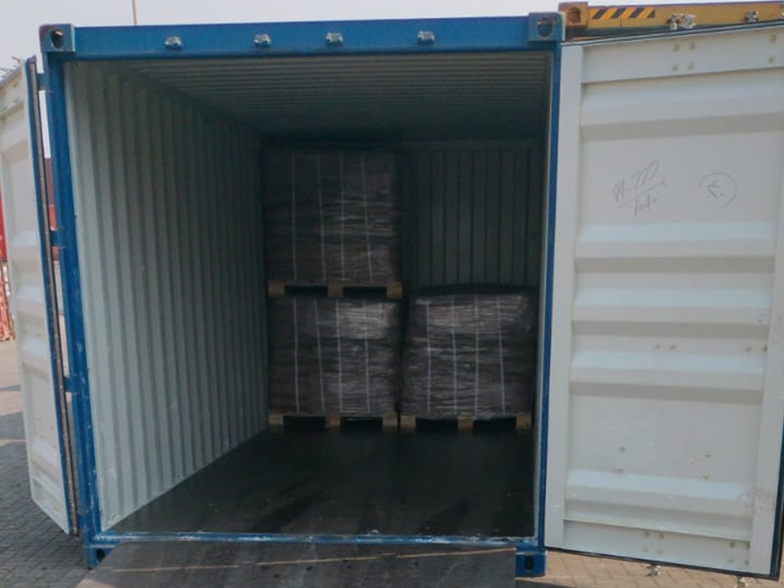Interior view of a 20-foot shipping container being loaded with shrink-wrapped pallets.