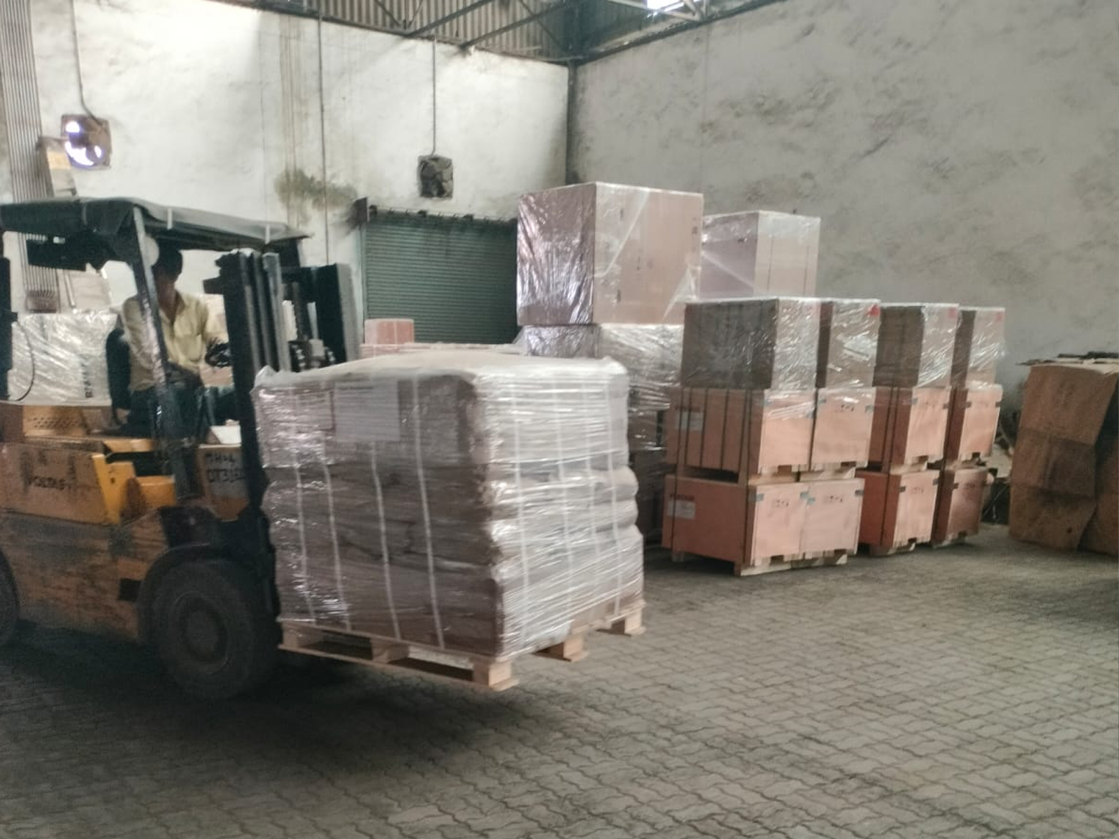 Forklift operator moving palletized cargo in a secure warehouse facility.